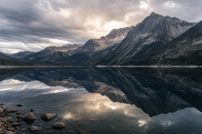Dark mountain lake reflecting clouds and peaks